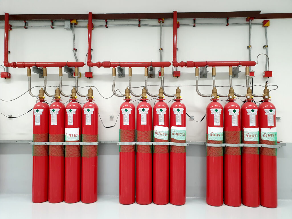 Clean agent fire suppression system with multiple red gas cylinders in a controlled environment.