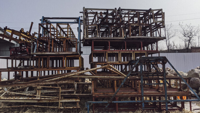 Stacked and rusted steel frameworks at a construction site under overcast sky