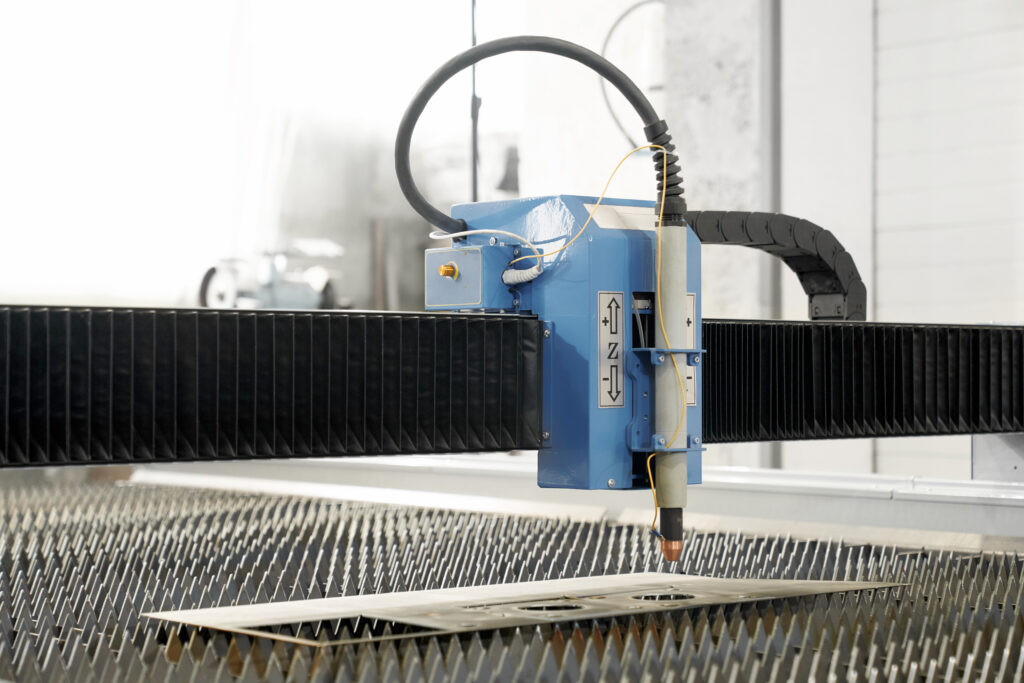 Close-up of an automated plasma cutting machine processing a metal sheet in a factory.