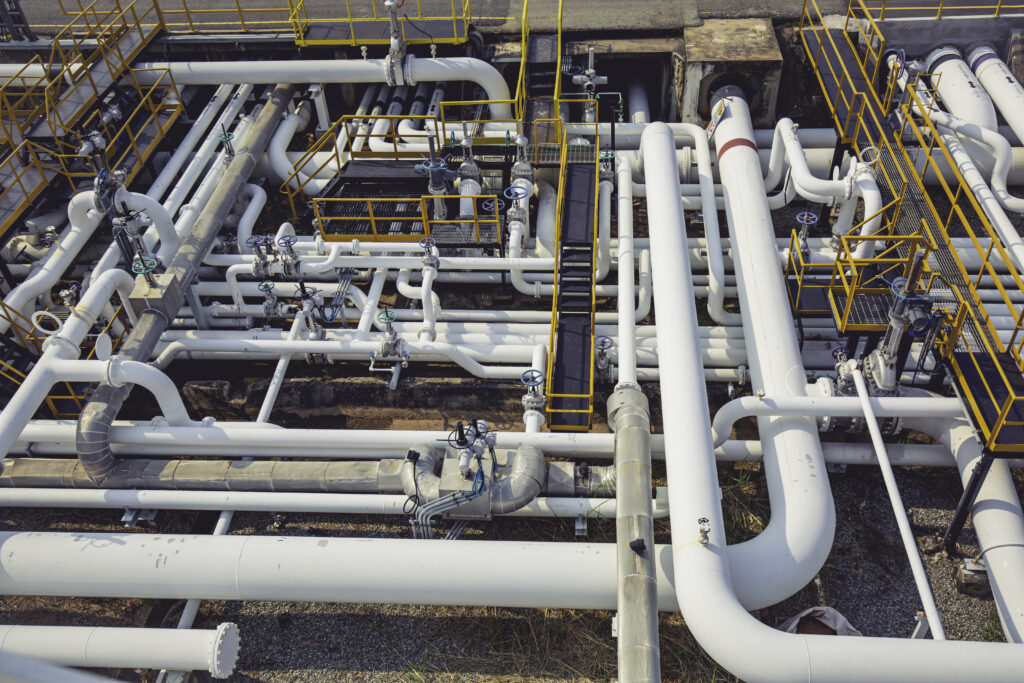 Aerial view of a complex network of steel pipes and walkways in an oil refinery.